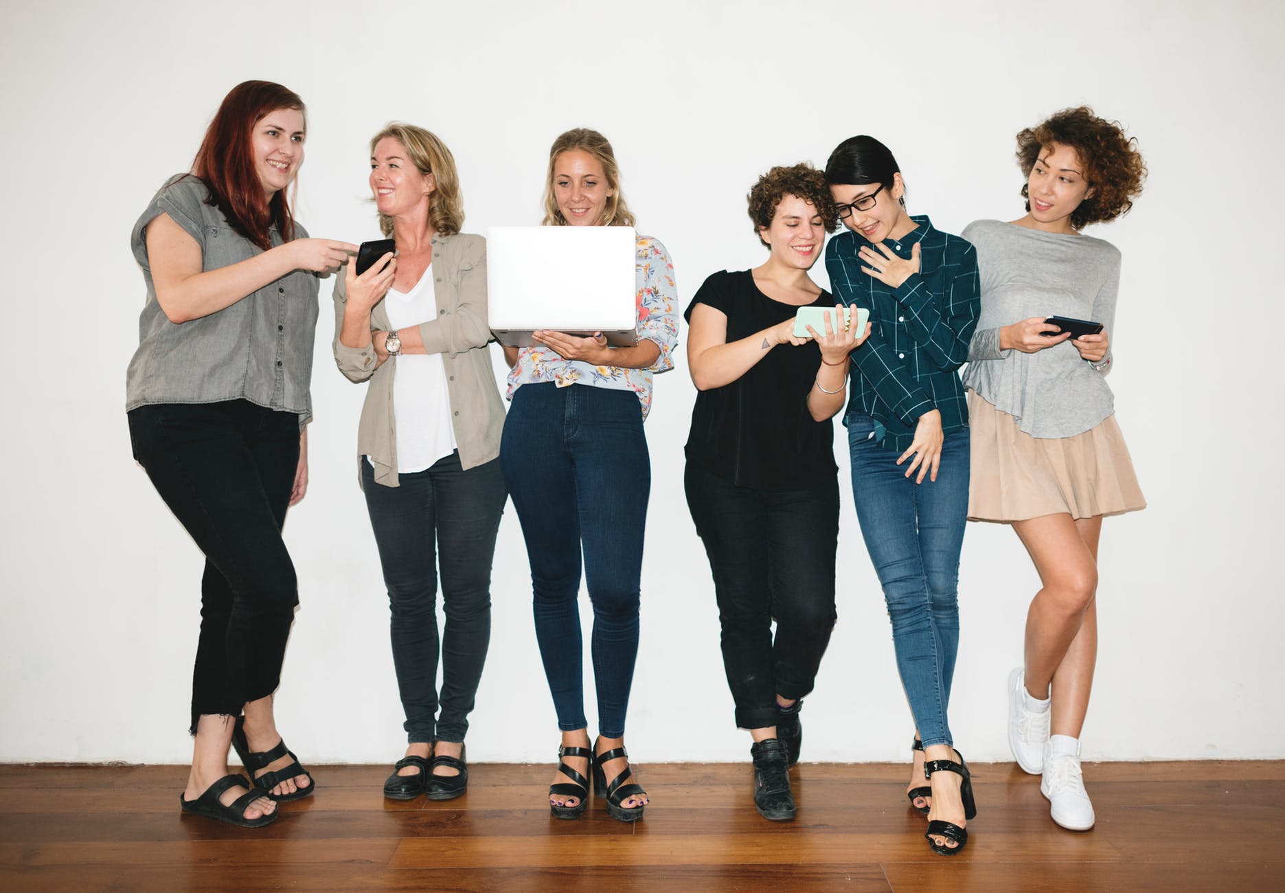 woman holding white laptop between women