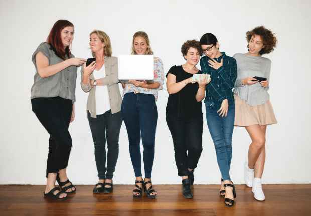 woman holding white laptop between women